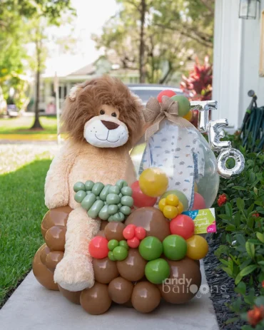 Safari-themed baby gift with a lion plush and onesie inside a stuffed balloon, ideal for welcoming a newborn
