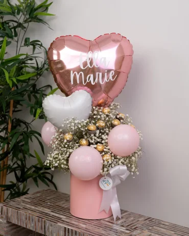 Personalized pink heart balloon for a baby girl in a luxury floral box with baby's breath and Ferrero Rocher chocolates.